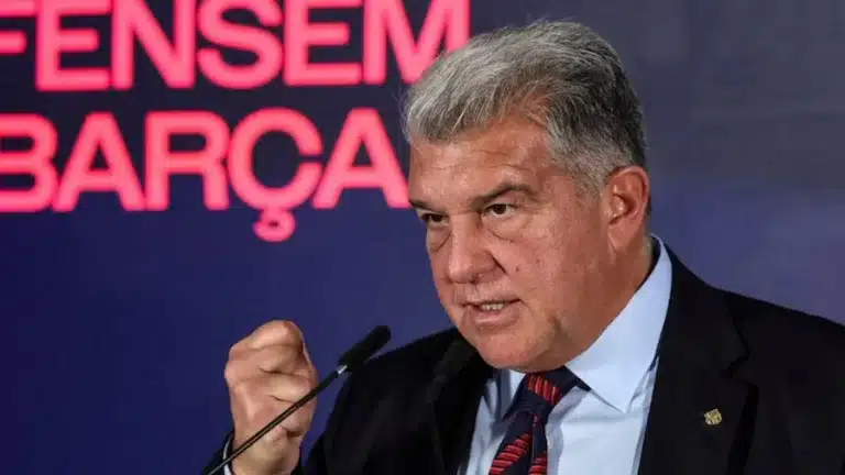 Joan Laporta gesticula con el puño cerrado ante un micrófono, con el lema Defensem el Barça al fondo