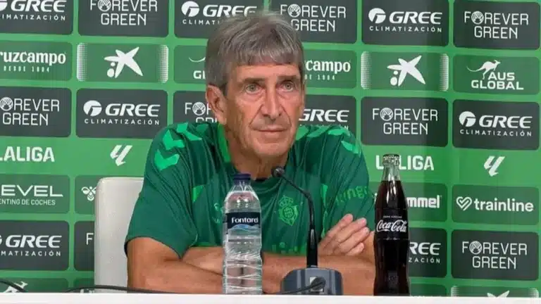 Manuel Pellegrini, con polo verde del Betis, en la sala de prensa con el fondo de patrocinadores del club