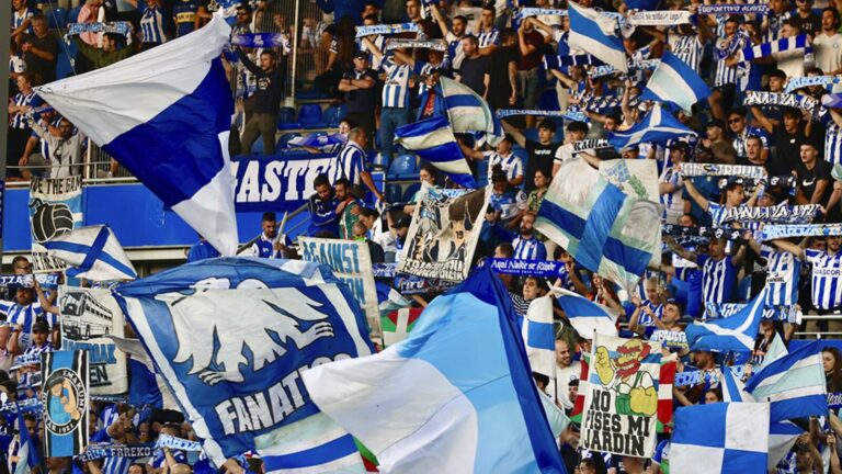 Aficionados de Iraultza 1921 con banderas, bombos y laureles en la grada de un estadio