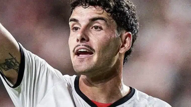 Sergio Camello señala con el brazo levantado durante un partido con la camiseta blanca de la franja del Rayo Vallecano