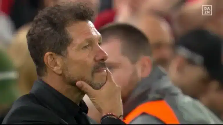 Simeone, con la mano en el mentón, sigue el partido desde la banda con el público del estadio desenfocado al fondo